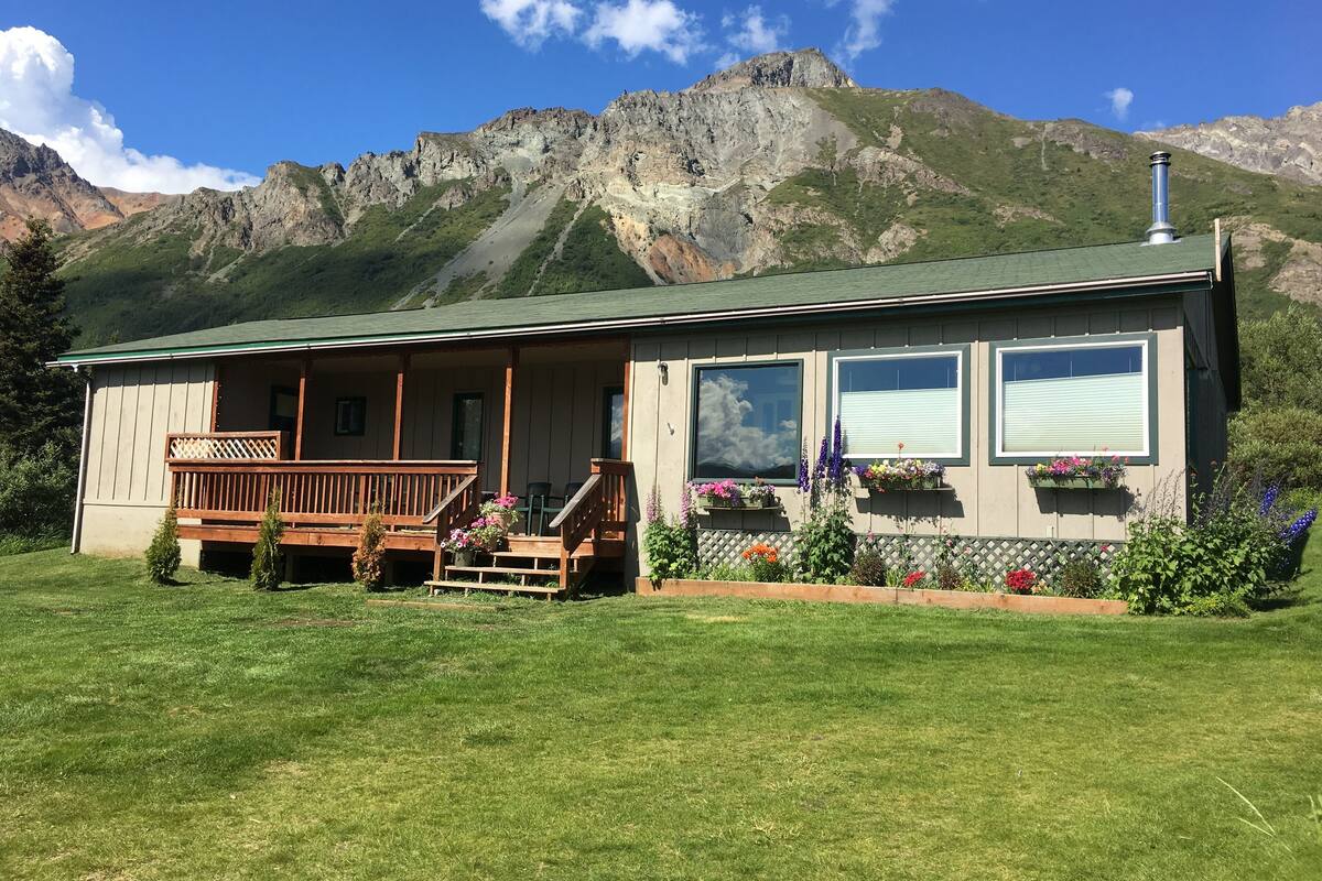 A lodge with a wooden deck, a covered porch, and flower boxes on the windows.