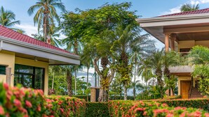 A pathway leading to a building with a red roof, surrounded by lush greenery and palm trees. - Hotel Manuel Antonio (Quepos)