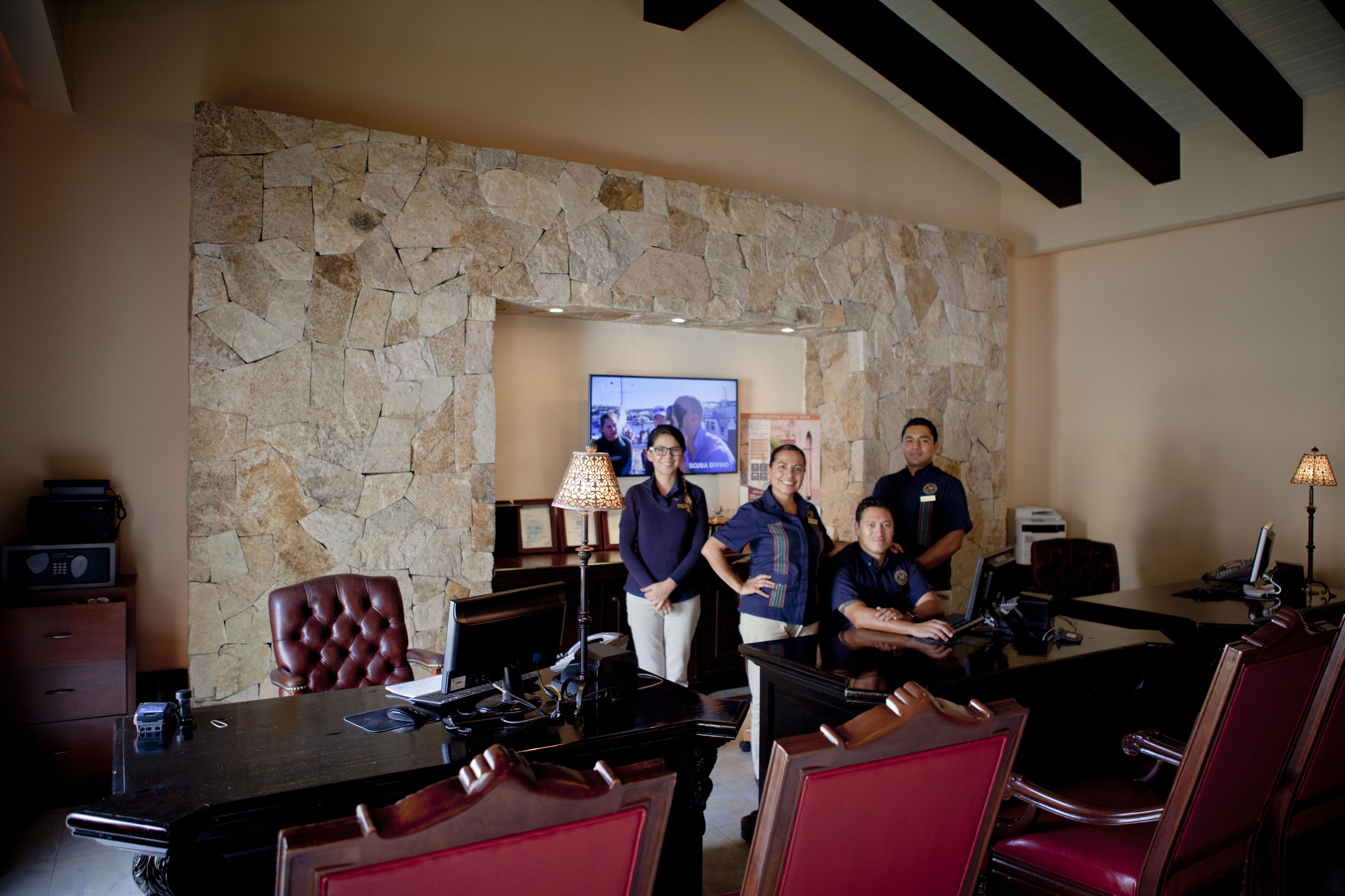 A lobby with stone walls, a TV, and a reception desk.