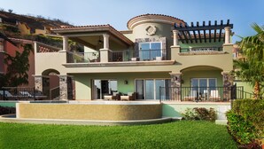 A two-story house with a balcony, a swimming pool, and a landscaped garden.
