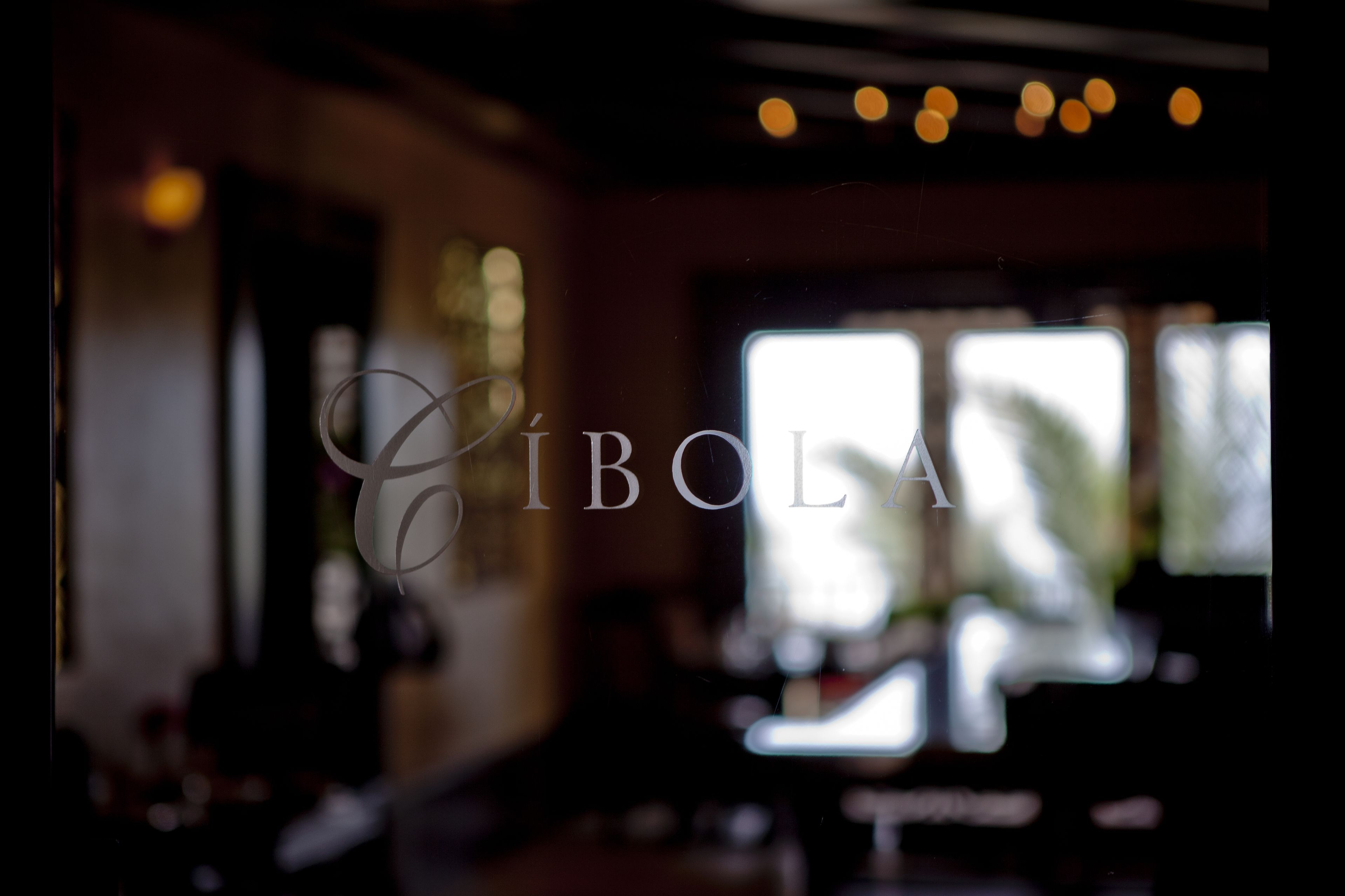 Une vue floue de l’intérieur d’un restaurant ou d’un café, avec le nom « Cibola » visible sur une vitre.