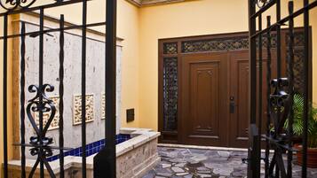 A courtyard with a tiled floor, a wooden door, and a metal gate.