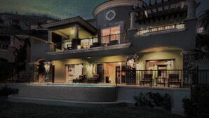 A two-story house with a balcony, a swimming pool, and a well-lit entrance.