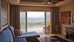 A living room with a sofa, a coffee table, and a view of the ocean.