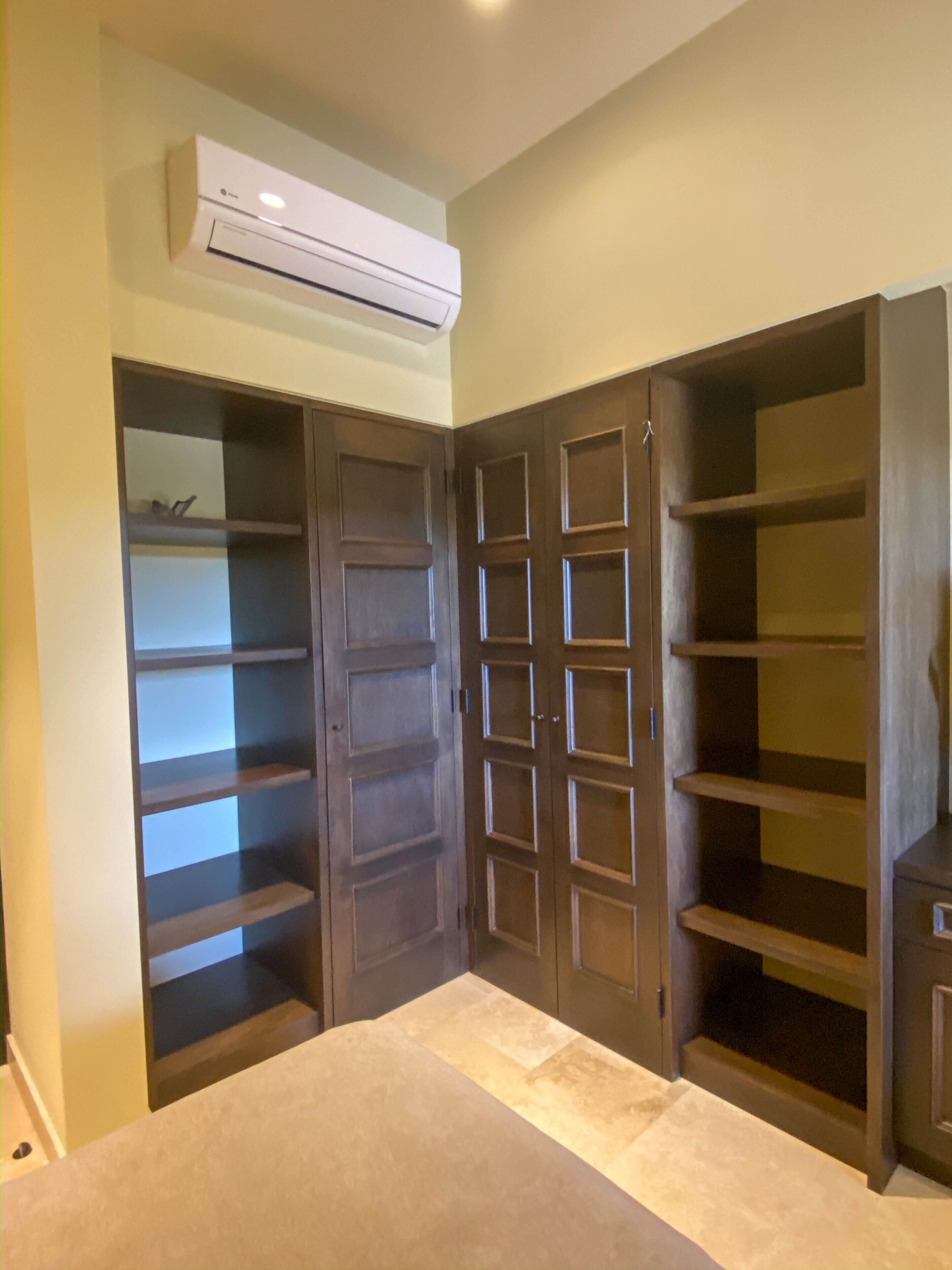 Un dormitorio con armario empotrado, cama y equipo de aire acondicionado.