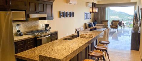 A modern kitchen with granite countertops, a built-in stove, and a large island with bar stools.