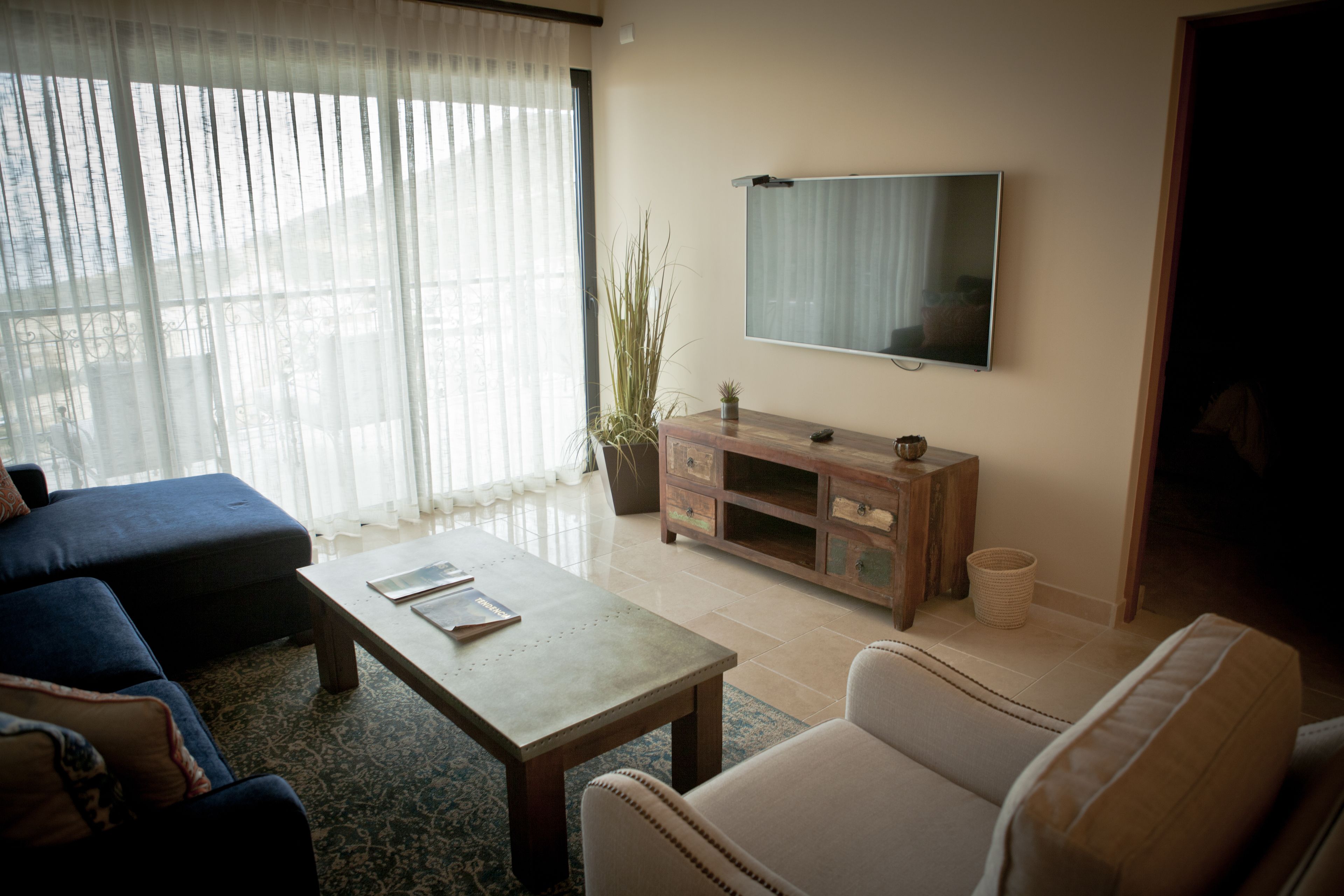 Ein Wohnzimmer mit Sofa, Sessel, Couchtisch, Fernseher und einem Blumentopf.