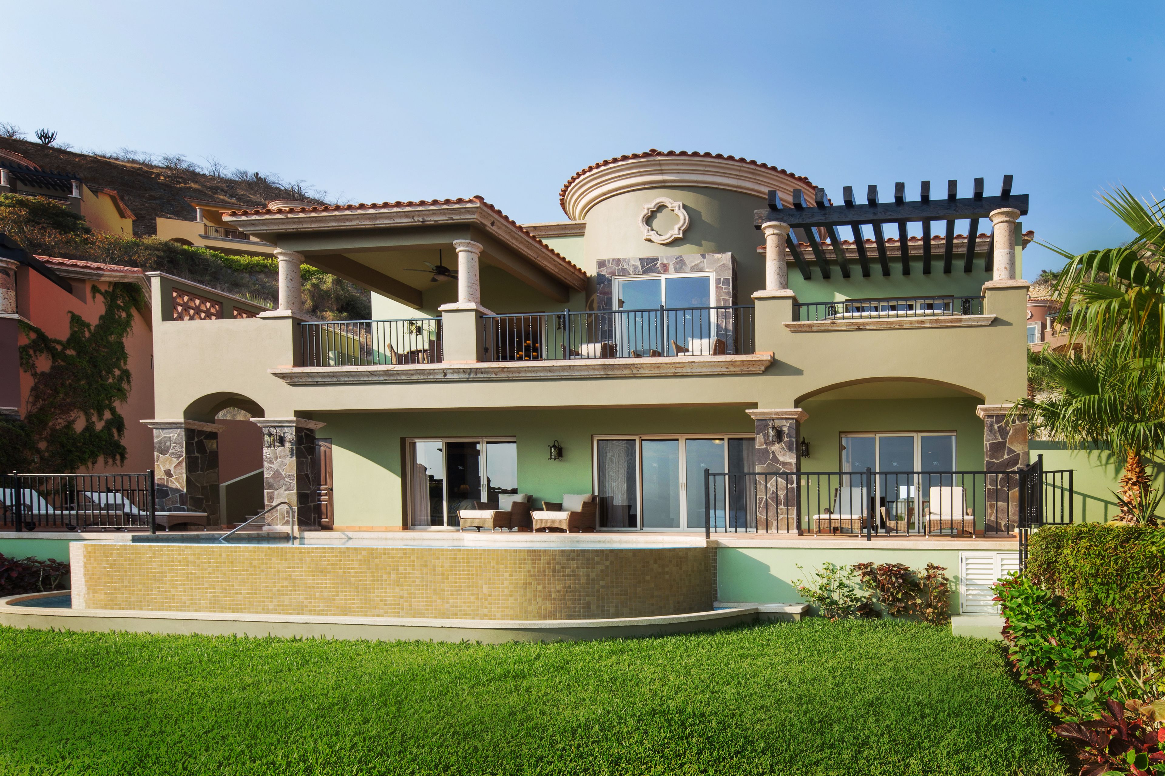 A two-story house with a balcony, a swimming pool, and a landscaped garden.
