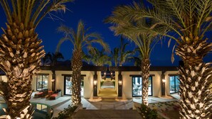 A modern resort with a pool area, palm trees, and a well-lit entrance. - Quivira Los Cabos Condos & Homes - Vacation Rentals (Cabo San Lucas)