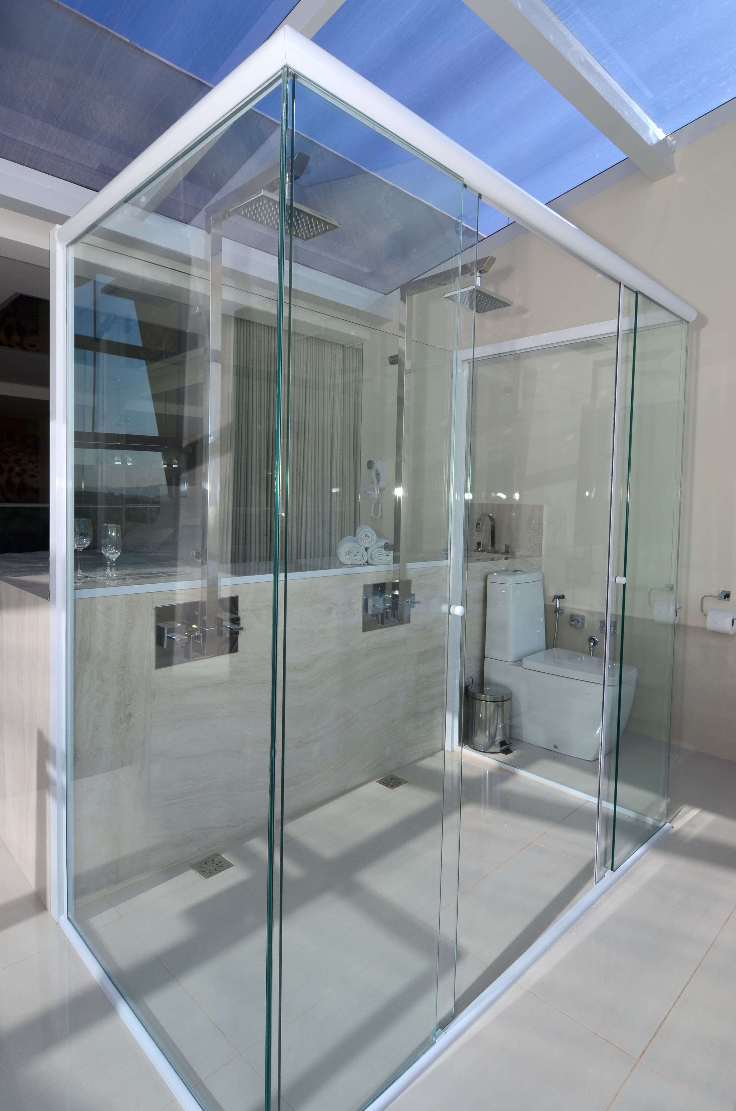 Un baño moderno con paredes de vidrio, ducha e inodoro.