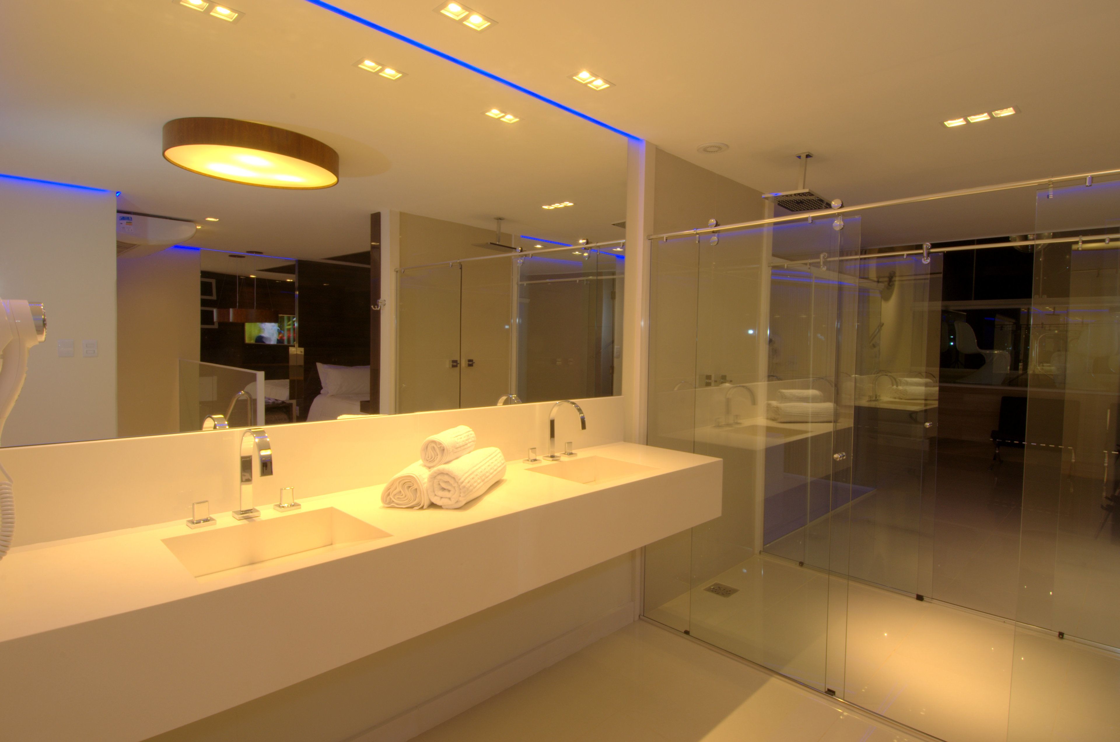 Une salle de bain moderne avec un grand miroir, un lavabo blanc et une cabine de douche en verre.