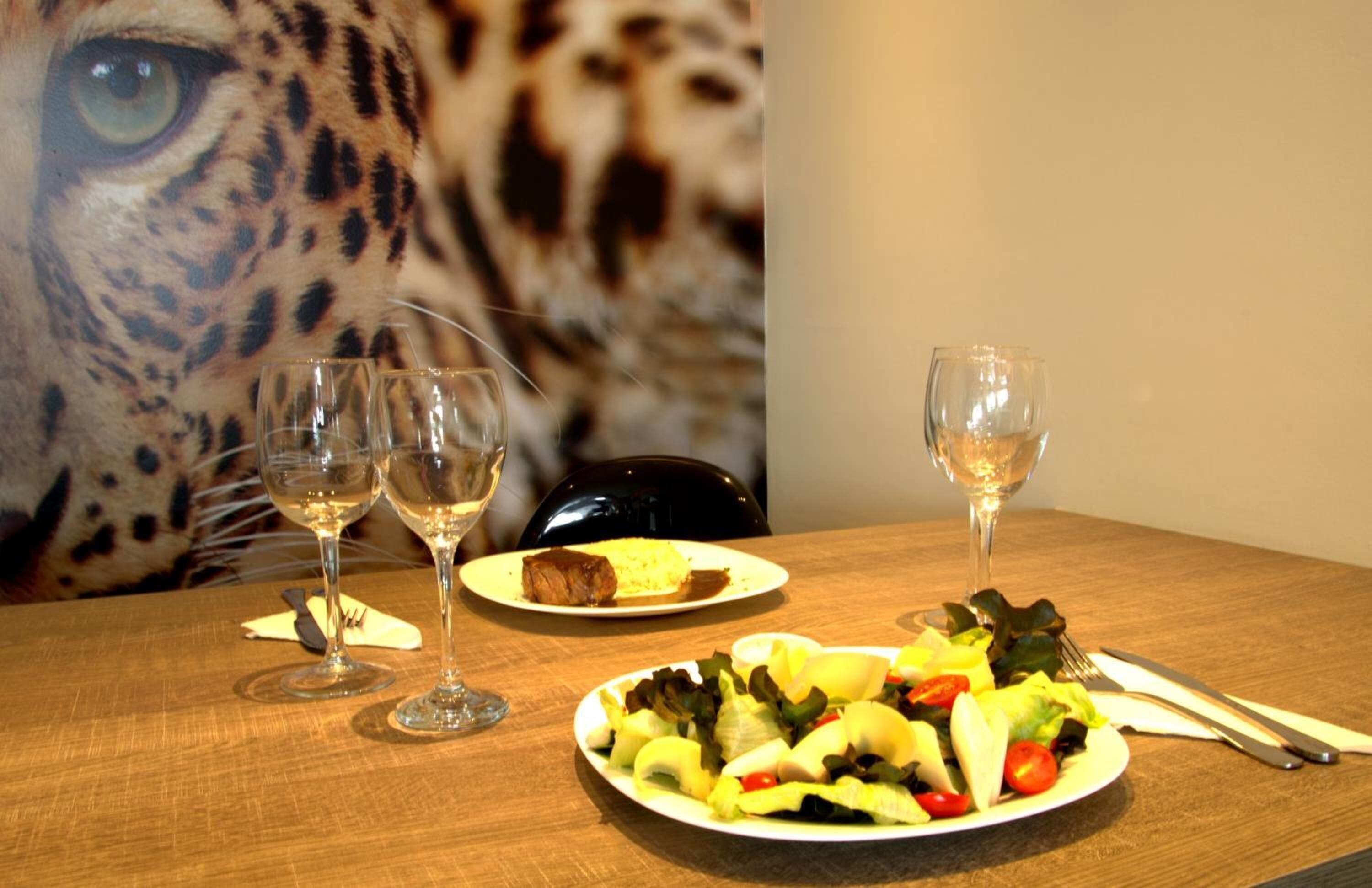 Une table à manger avec deux assiettes de nourriture, deux verres à vin et des couverts.