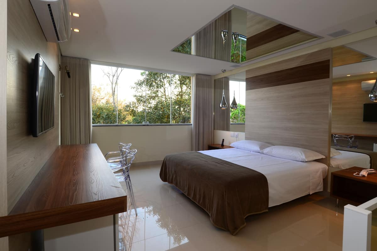 A modern hotel room with a large bed, a desk, and a TV.
