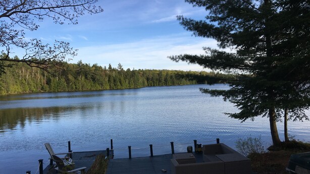 A lakeside deck with seating and a dock extending into the water. - QuickStay - Heavenly Cottage (Beautiful Lake Views) (Bracebridge)