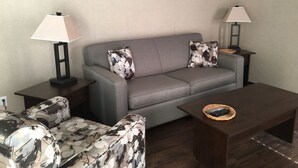A living room with a grey sofa, two matching armchairs, two floor lamps, and a coffee table with a basket. - QuickStay - Heavenly Cottage (Beautiful Lake Views) (Bracebridge)