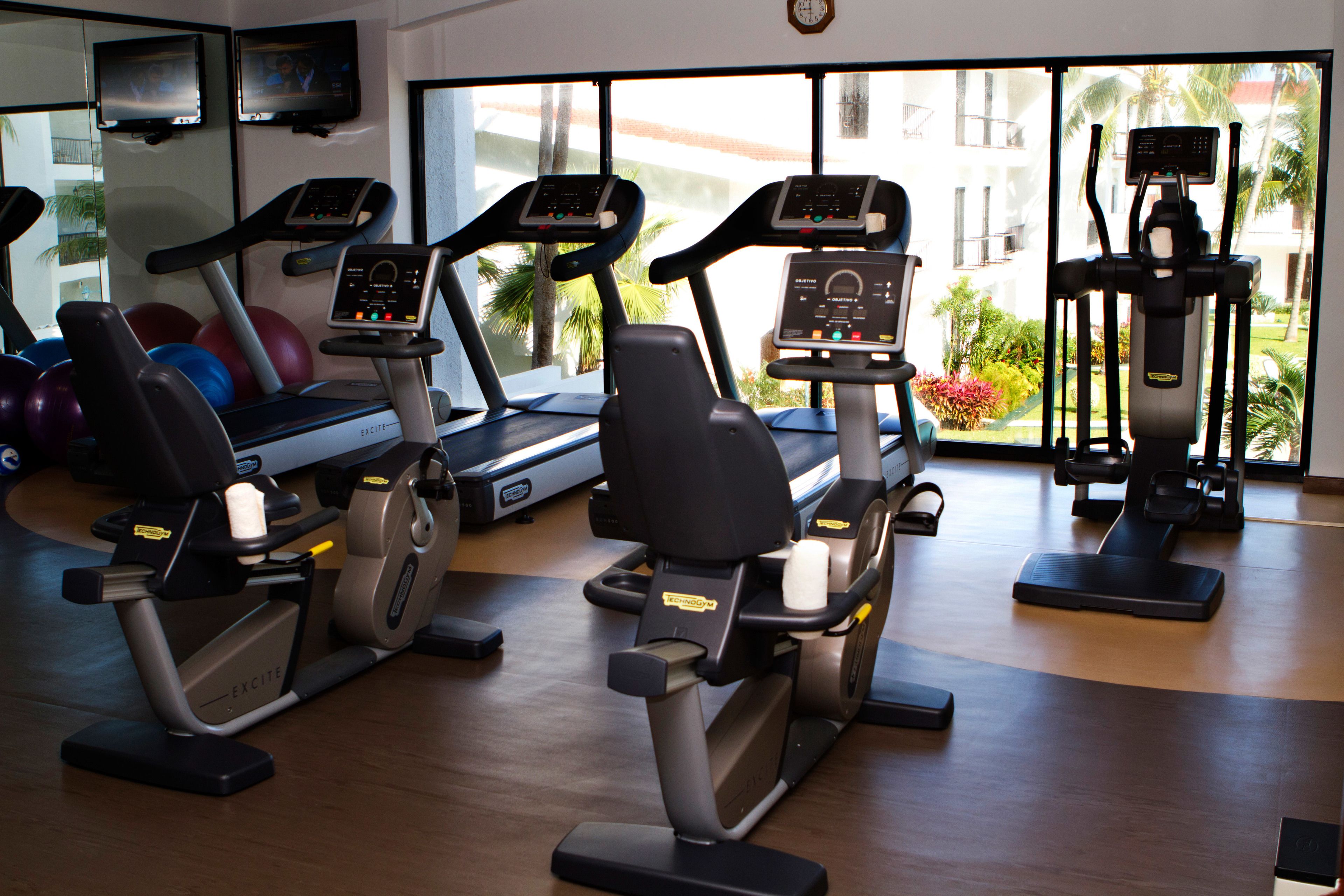 A gym with stationary bikes, treadmills, and exercise balls.