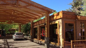 Un espace extérieur abrité, doté d’une pergola en bois, d’un banc et d’une voiture garée à proximité.