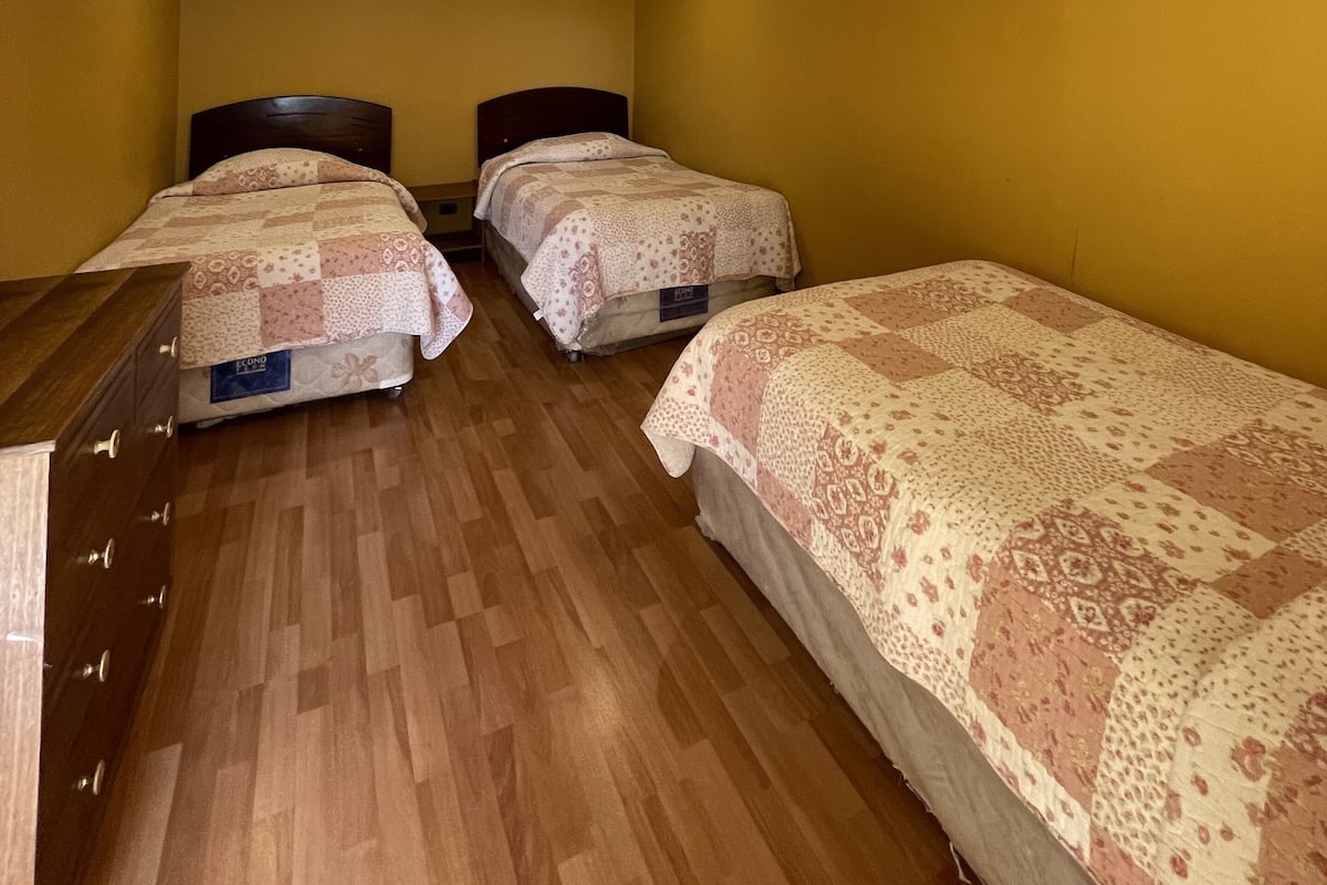 Une chambre avec deux lits, un plancher en bois et une commode.