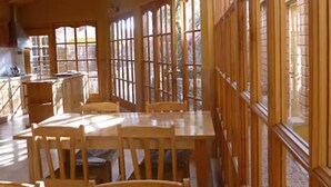 Un intérieur en bois comprenant un coin repas, de grandes fenêtres et une cuisine.