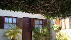 Un edificio con il numero 6 sulla porta, piante in vaso e una zona patio con piastrelle.