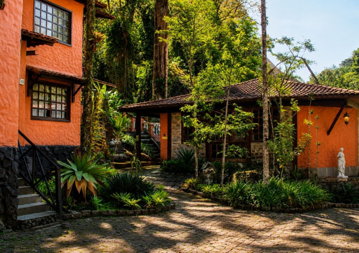 Un edificio con una escalera de piedra, una puerta de madera y una estatua en el jardín.