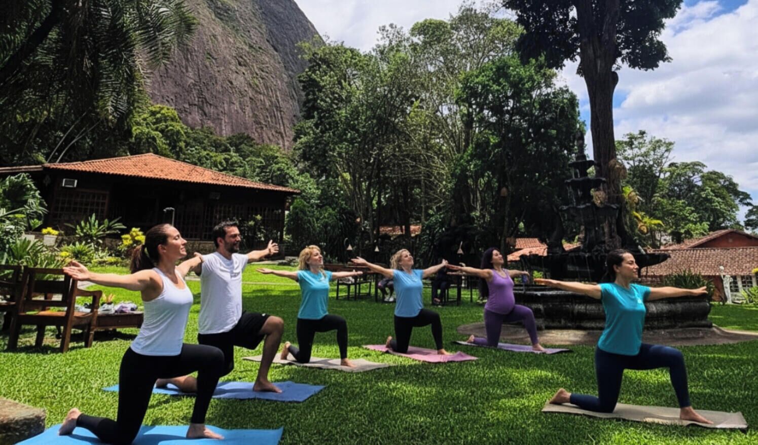 A group of people performing yoga in an outdoor setting with a mountain in the background.