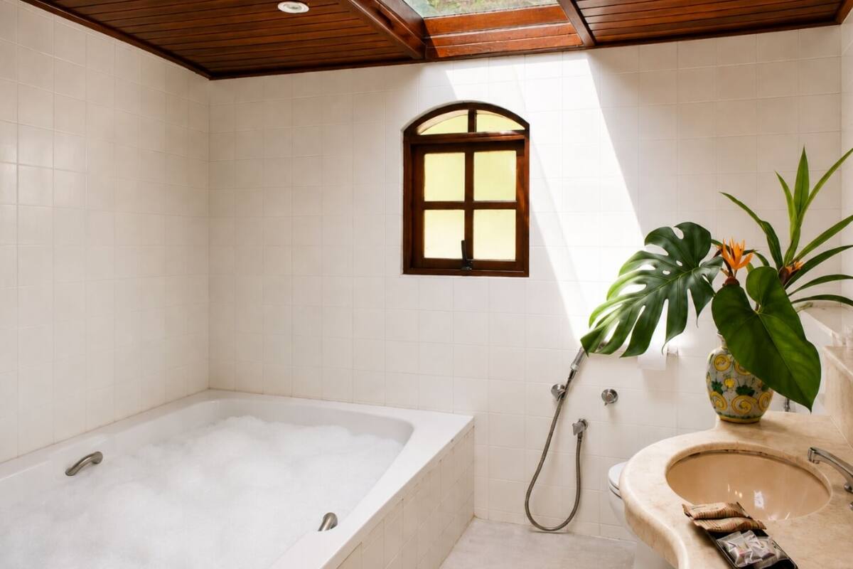 A bathroom with a bathtub, a shower, a sink, and a window.