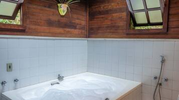 Un baño con una bañera grande, ducha y ventana con planta.
