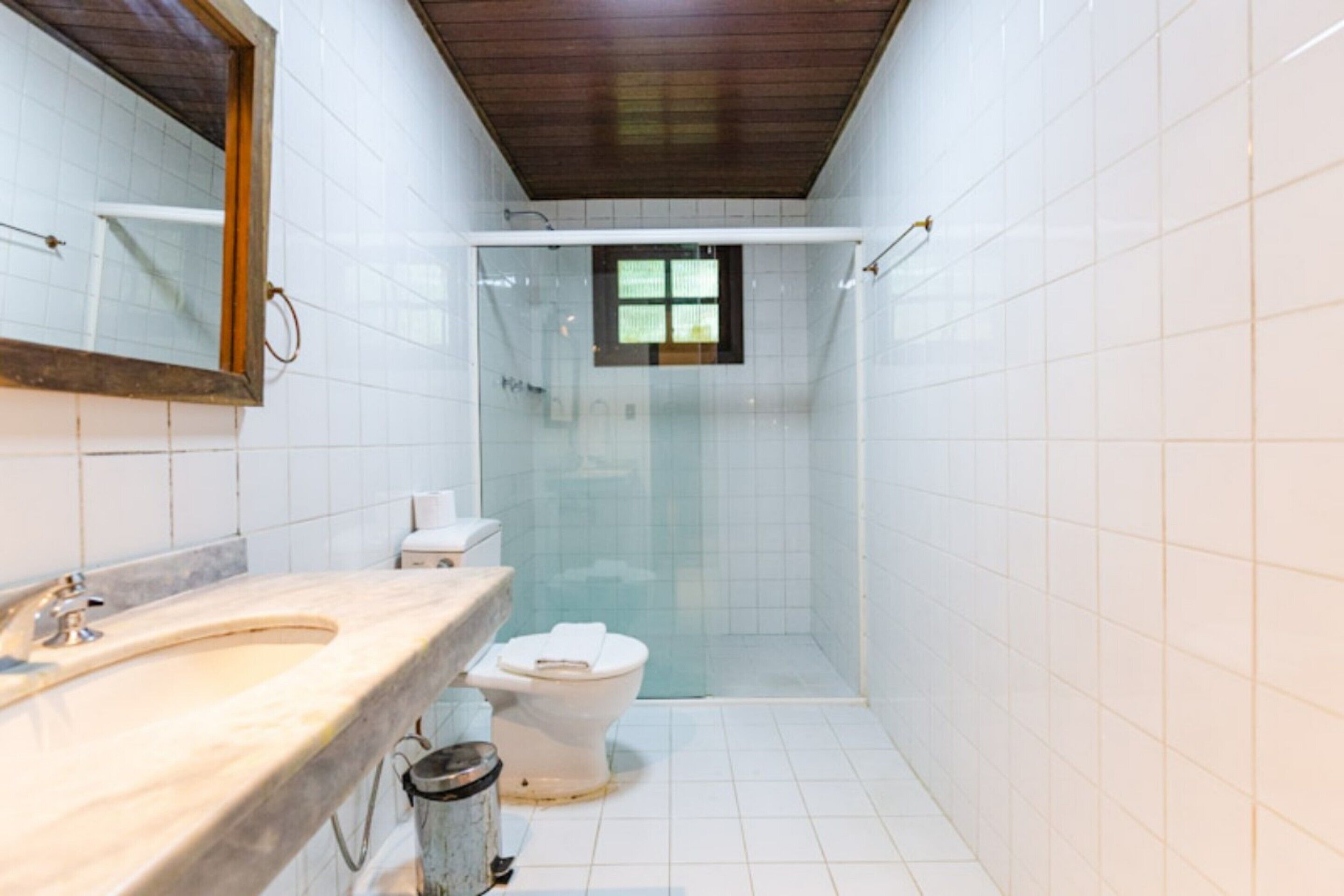 Uma casa de banho com lavatório de mármore, sanita e cabine de duche com portas de vidro.