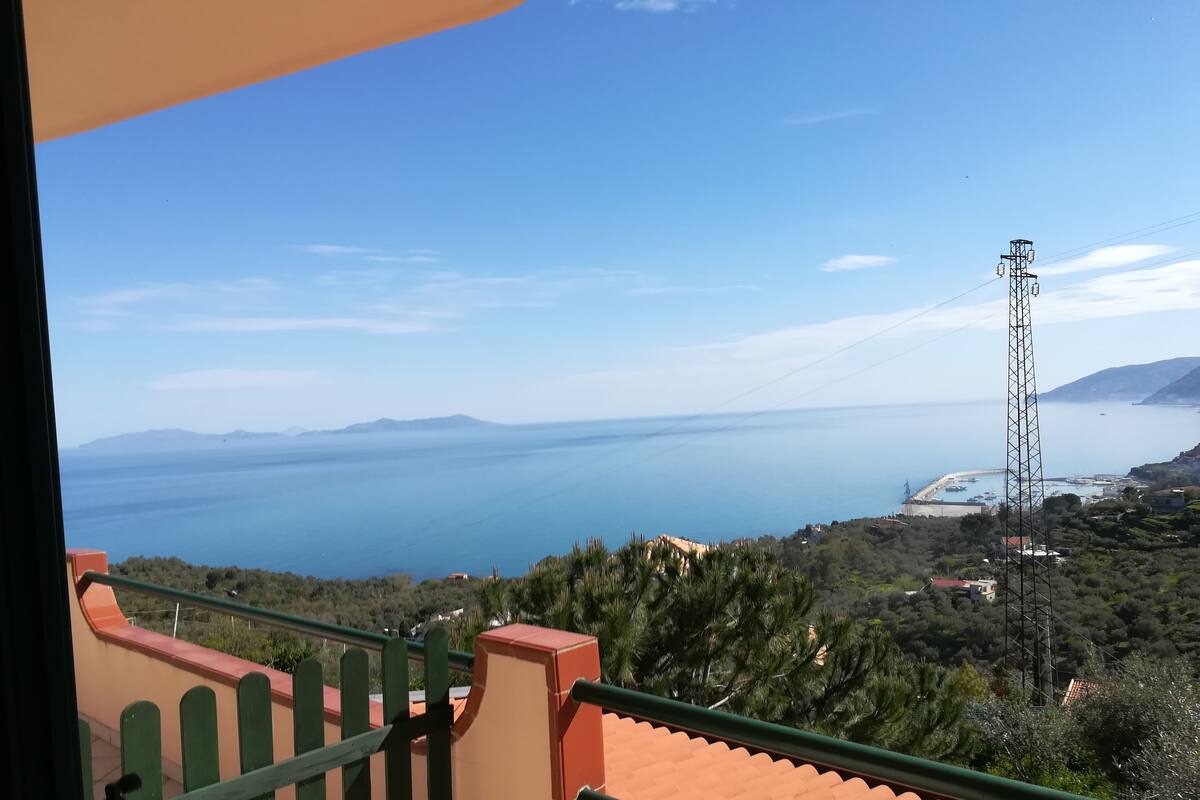 A balcony with a view of the sea and distant mountains.