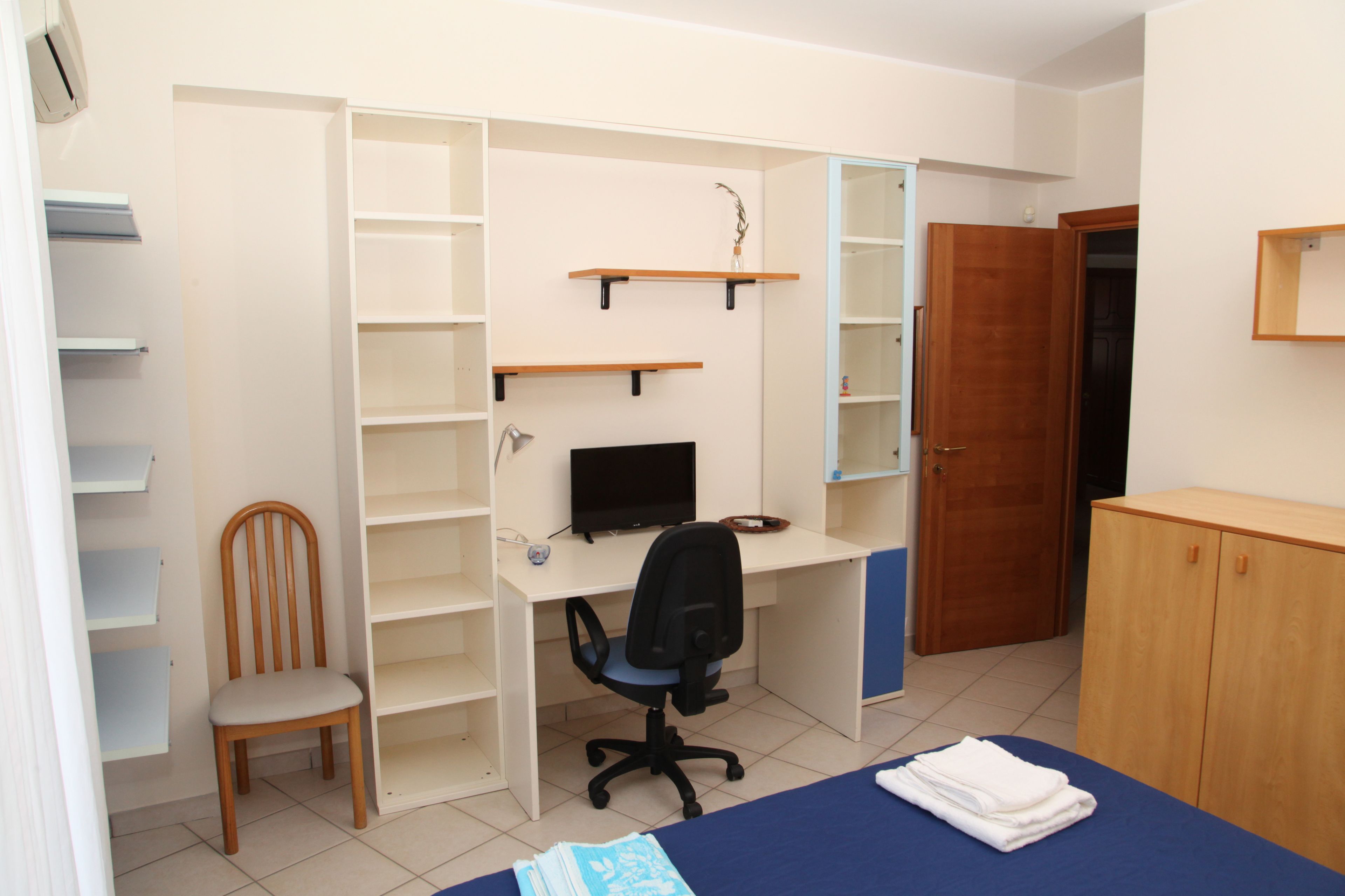 Ein Schlafzimmer mit Bett, Schreibtisch, Stuhl und Kleiderschrank.