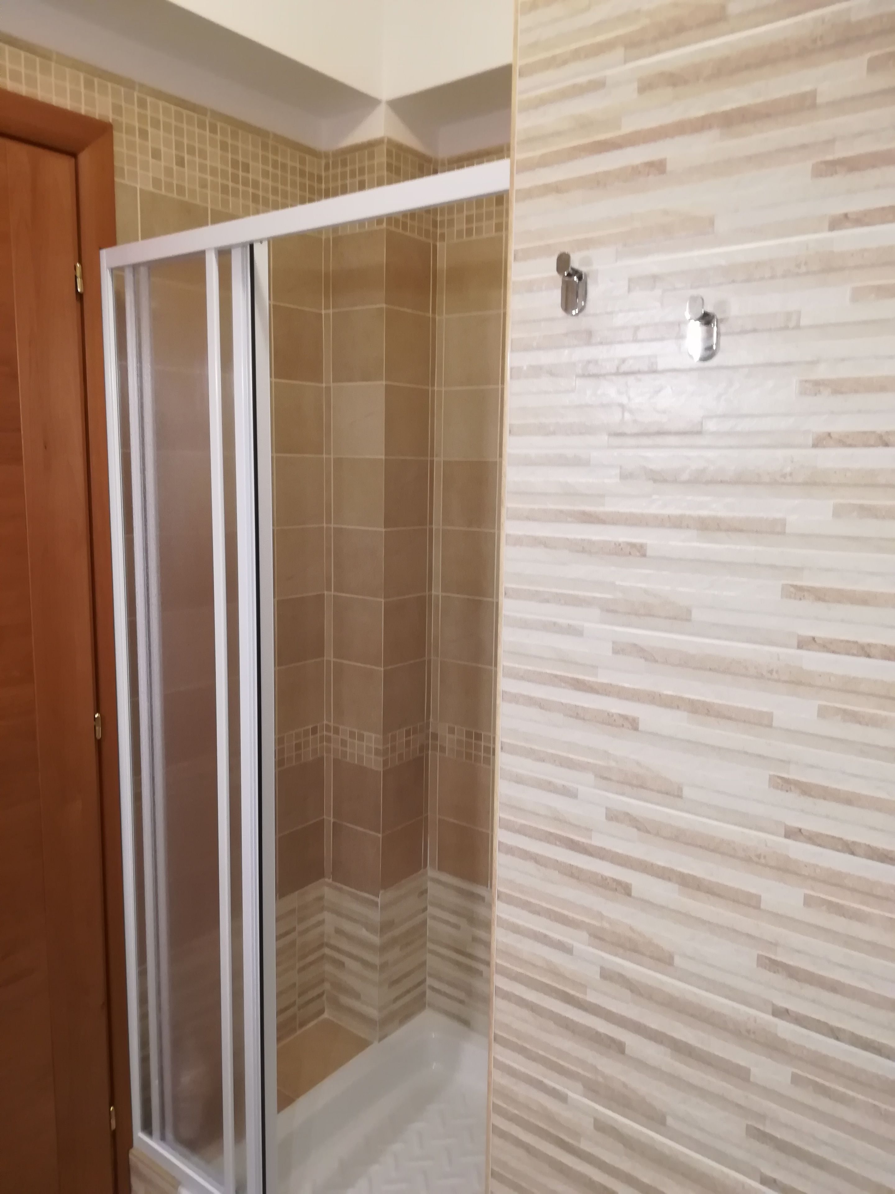 Un espace douche doté d’une porte en verre et de murs carrelés.