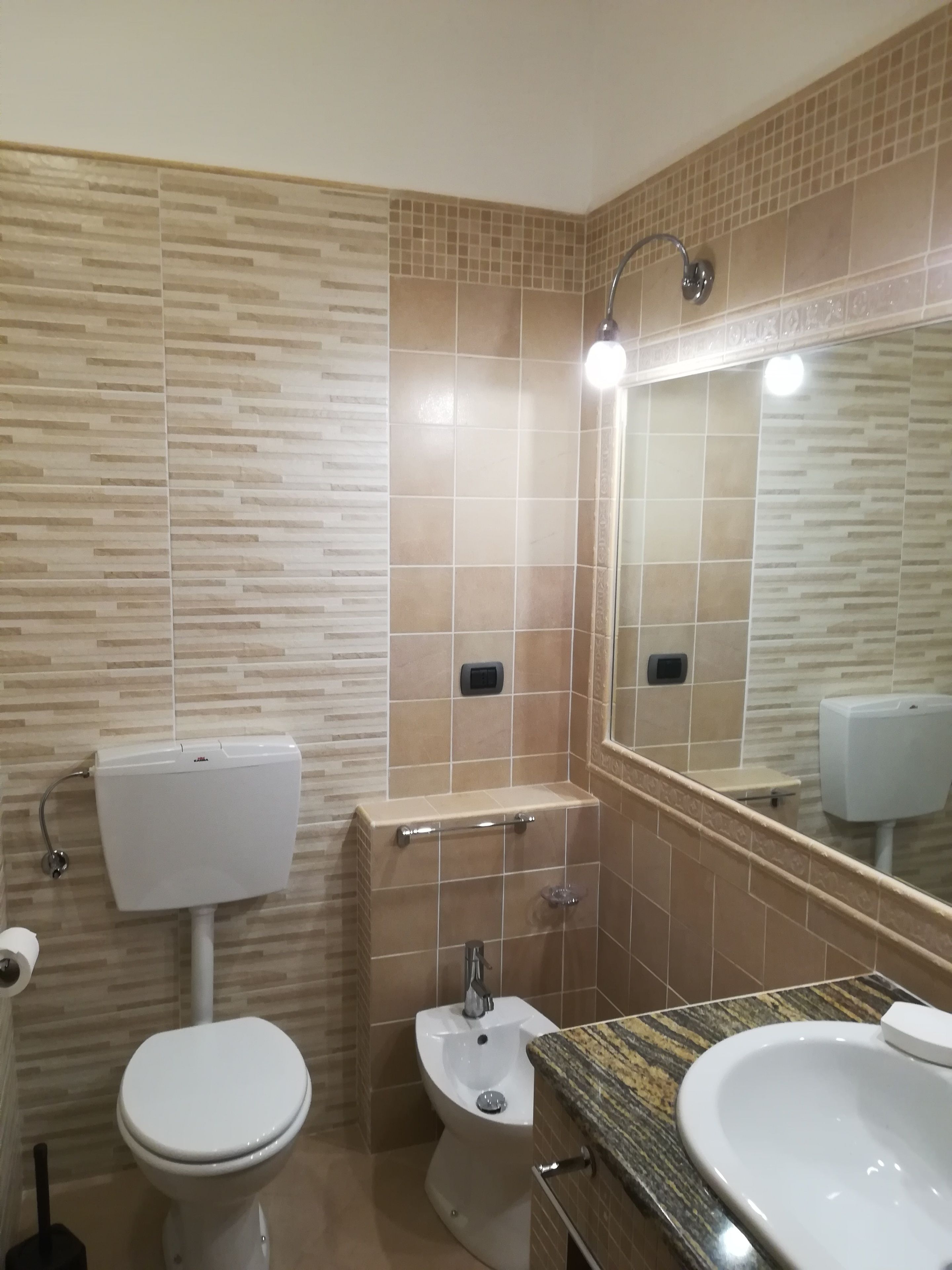 Un baño con inodoro, bidé y lavamanos, todo con accesorios modernos.