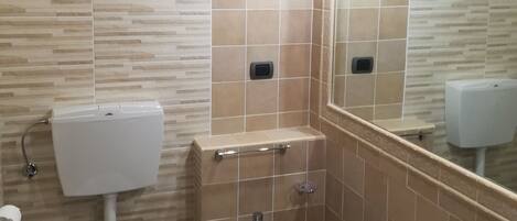 A bathroom with a toilet, bidet, and sink, all with modern fixtures.