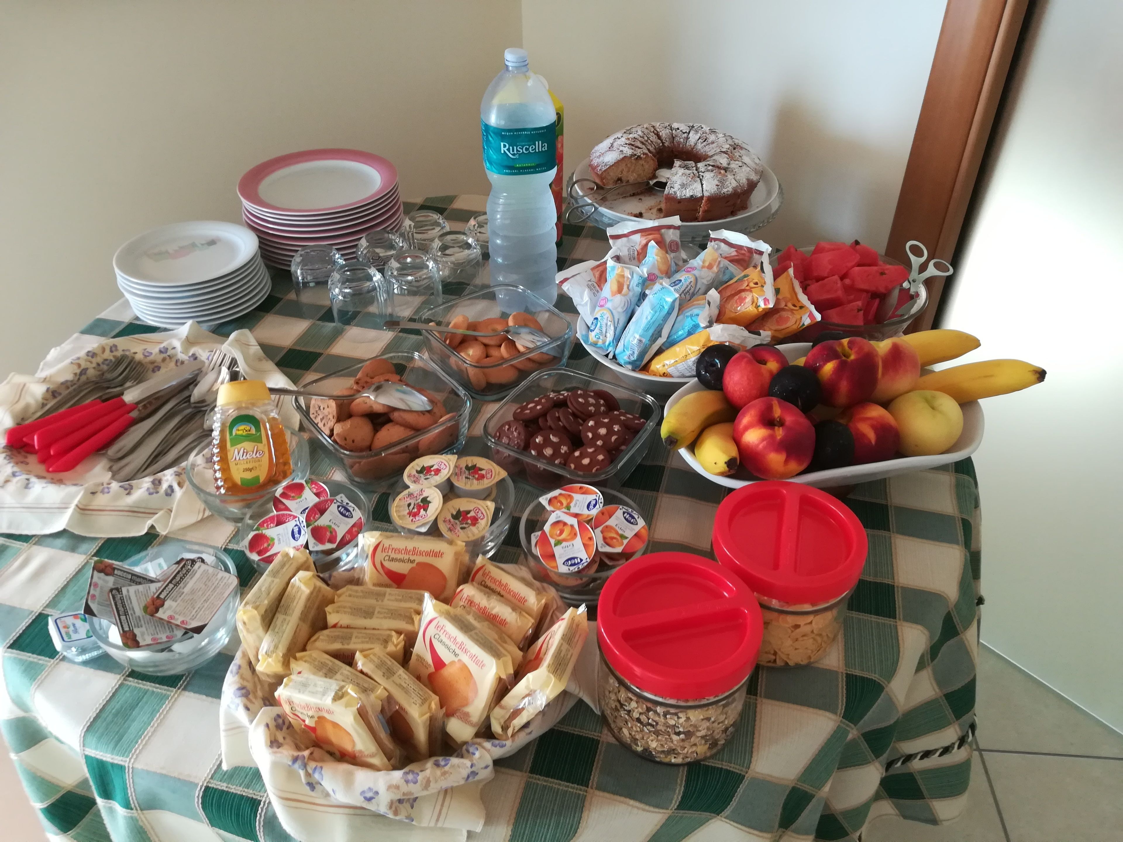 Un tavolo per buffet con diversi cibi, tra cui frutta, pasticcini e salse.