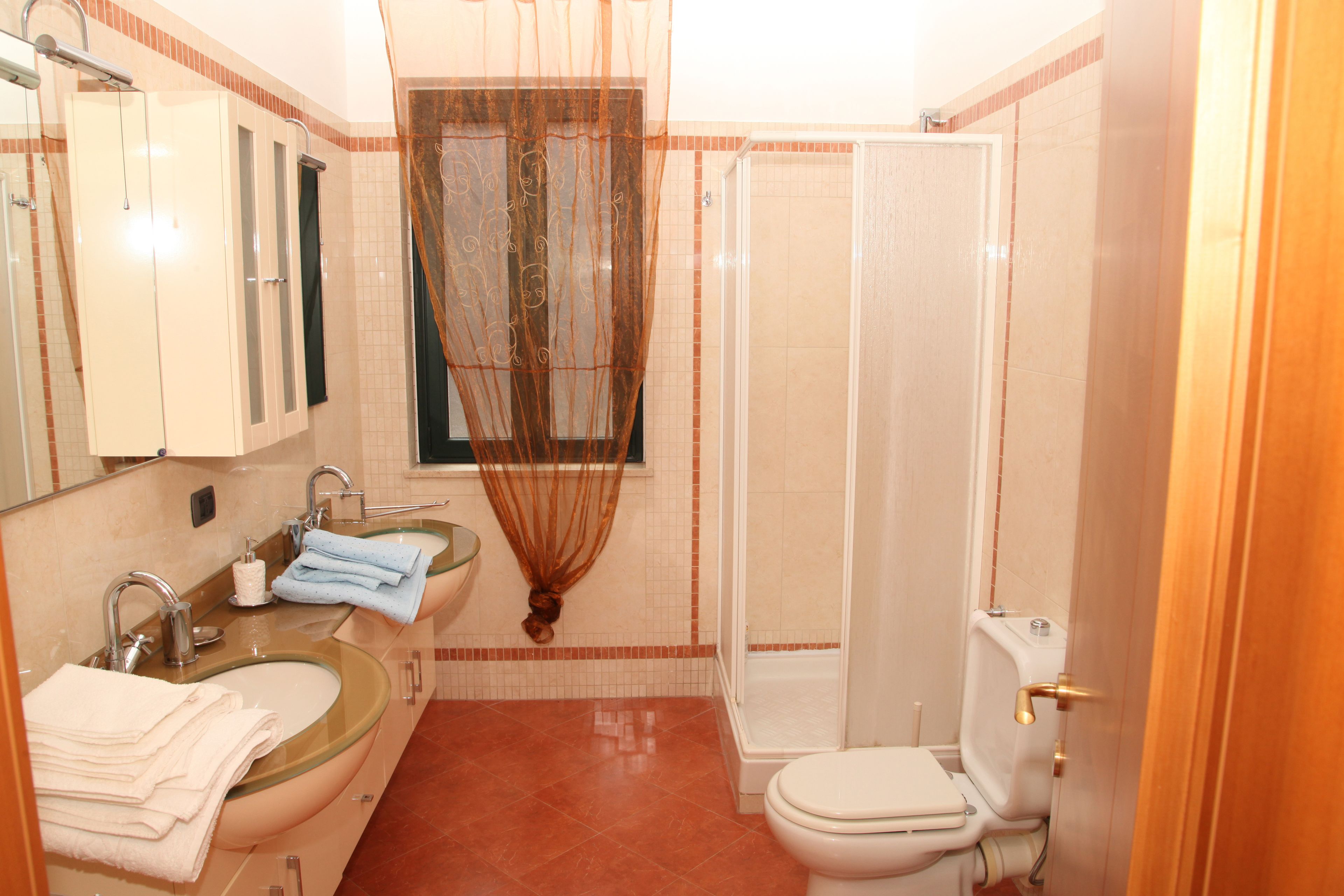 Ein Badezimmer mit einer Duschkabine, einer Toilette und zwei Waschbecken mit Spiegeln.