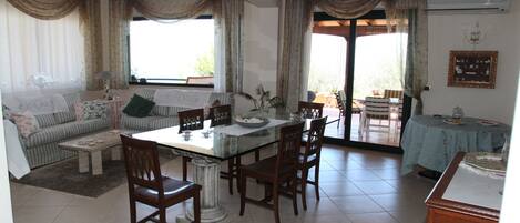 A spacious living area with a dining table, chairs, a sofa, and a coffee table.