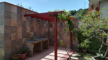 Un’area patio con un pergolato, una panchina e piante in vaso.