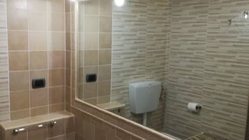 Een badkamer met een toiletbril, een wastafel, een spiegel en een zeepdispenser.