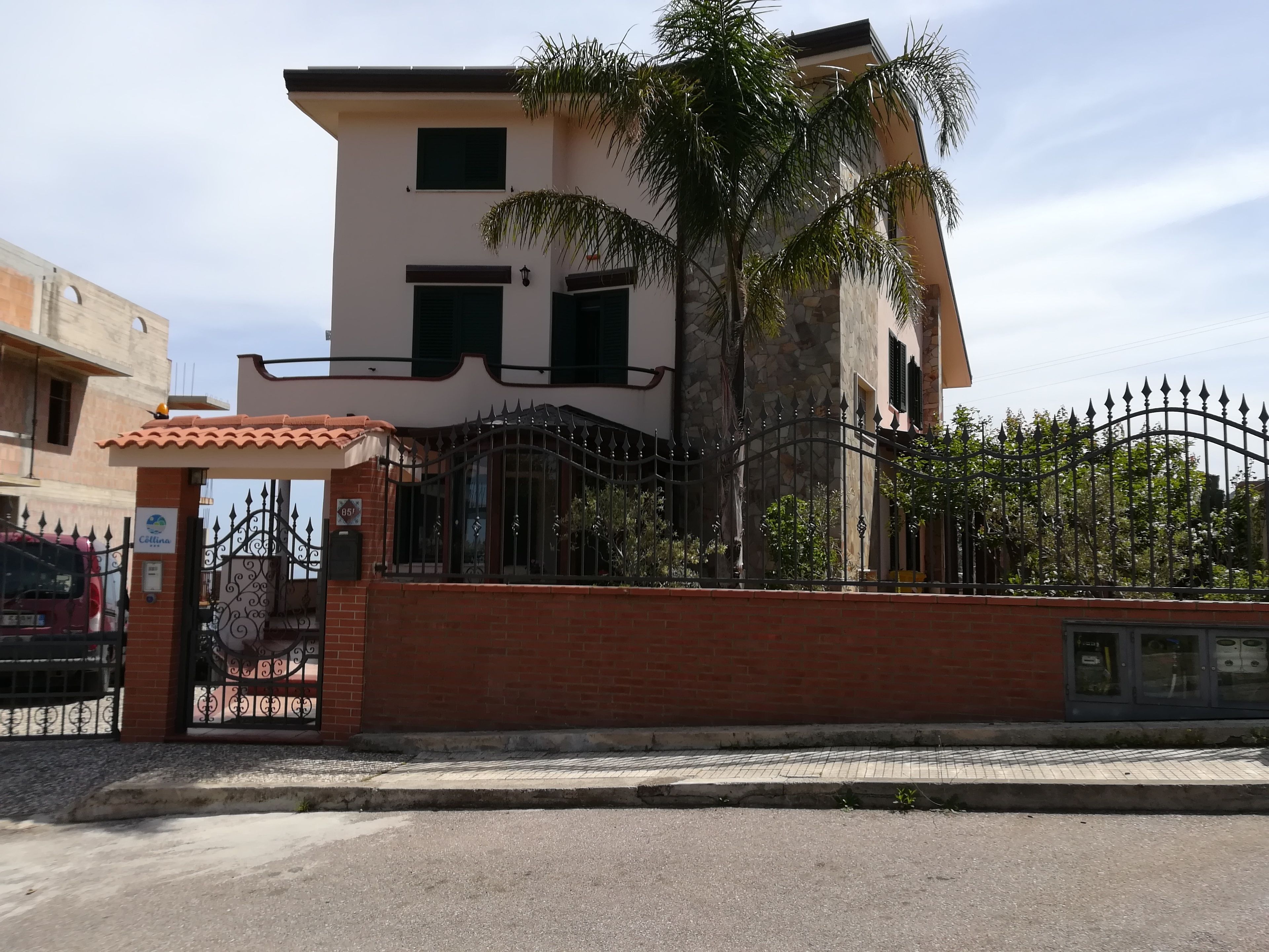 A two-story building with a tiled roof, a gated entrance, and a paved driveway.