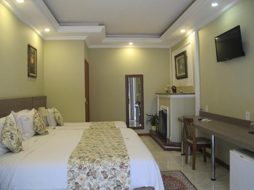 Quarto de hotel com uma cama grande, uma escrivaninha, uma televisão e uma lareira.