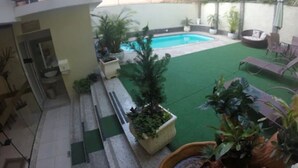 A backyard with a swimming pool, green artificial turf, and potted plants. - Pousada Princesa Isabel Dom Pedro (Petrópolis)