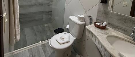 Un baño moderno con ducha envuelta en vidrio, inodoro y tocador con lavamanos.