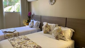 A hotel room with two beds, a large window with curtains, an air conditioning unit, and a decorative wall piece. - Pousada Princesa Isabel Dom Pedro (Petrópolis)