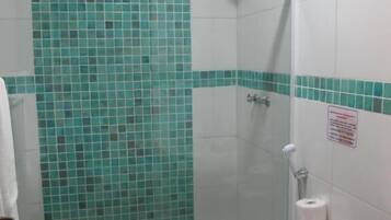 Un baño pequeño con ducha, inodoro y lavamanos.