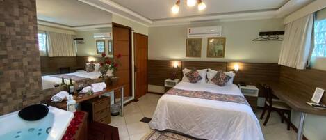 A hotel room with a large bed, a separate sitting area, a bathtub, and a desk with a chair.