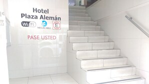 Una escala que condueix a l'entrada d'un hotel, amb indicadors de WiFi, Megacable i serveis E, i un cartell que diu "PASE USTED".