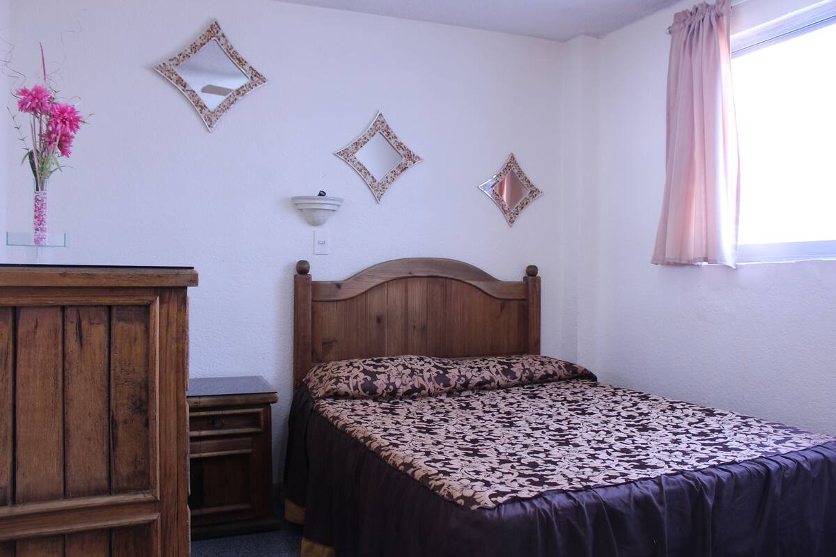 A bedroom with a wooden bed, a dresser, and a mirror on the wall.