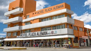 Un hotel de diverses plantes amb balcons i un cartell que diu "HOTEL PLAZA ALEMAN".