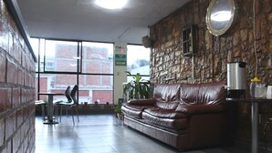 Un vestíbul amb un sofà de cuir, una màquina de cafè i una paret de pedra.